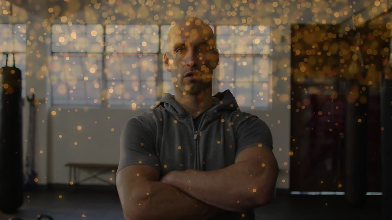 Trainer standing arms-crossed in gym bokeh rising and gliding over face and punchbag evoking talk