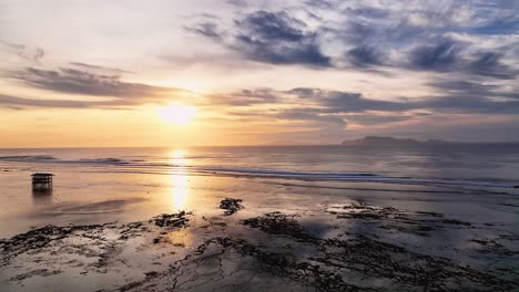 Drone-clip-of-beautiful-reflection-of-golden-sunset-on-calm-lagoon-and-open-ocean-waves-at-G-land,-Java,-Indonesia