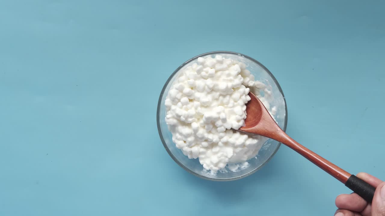 queso cottage en un cuenco de vidrio con cuchara de madera