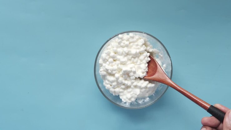 Fiocchi di latte in una ciotola di vetro con un cucchiaio di legno