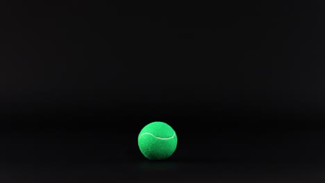 a tennis ball bounces against a dark background