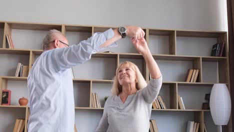 happy elderly couple dancing and twirling at home