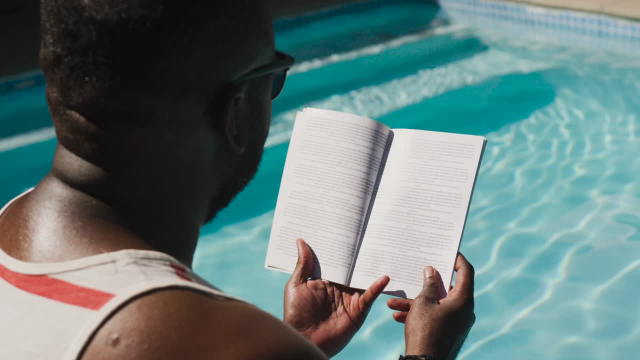 Man sitting poolside flipping pages after flip smoothing paperback keeping place, copy space