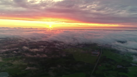 Alta-Vista-Aérea-De-Un-Sol-Amarillo-Sobre-Las-Nubes-Blancas-Con-Un-Paisaje-Verde-Debajo