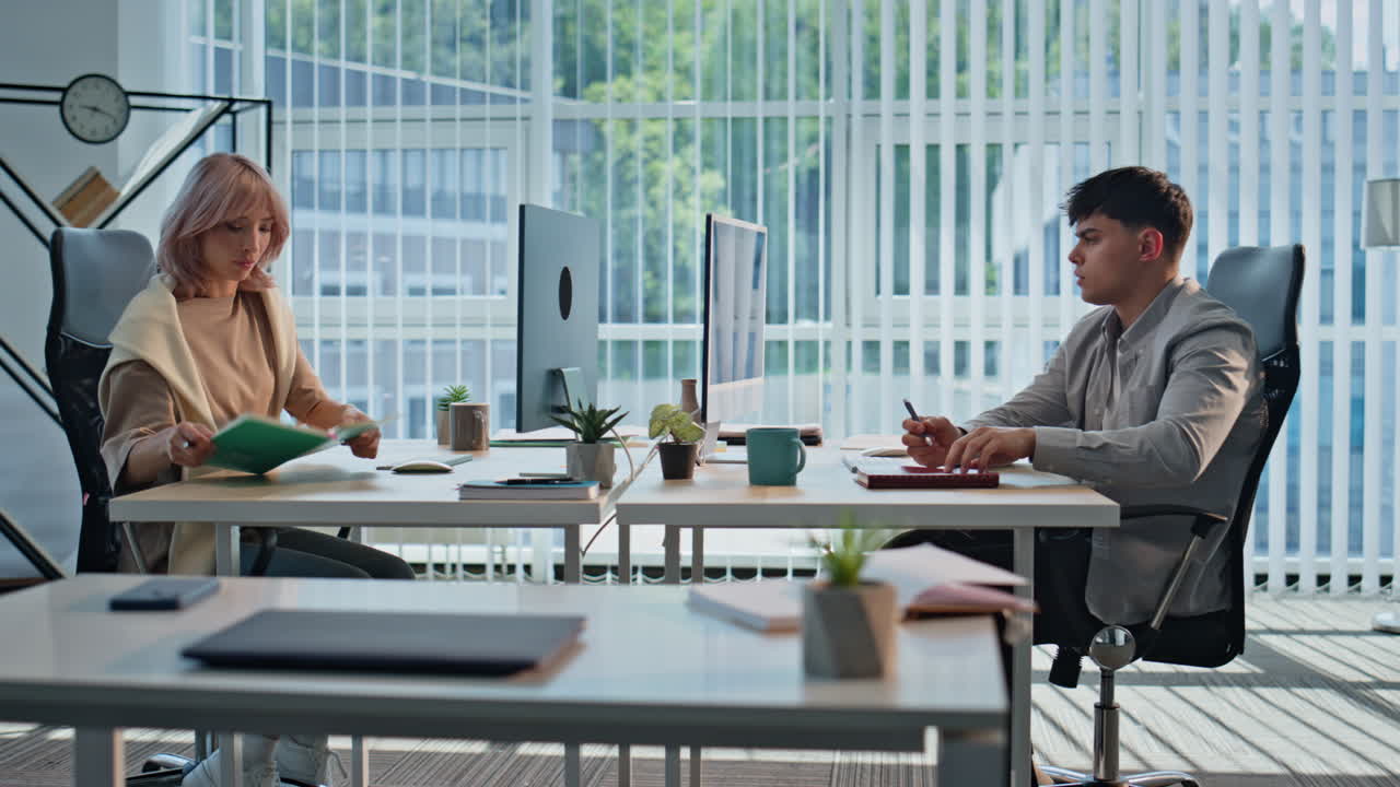 Couple colleagues working computers together planning project at panoramic room