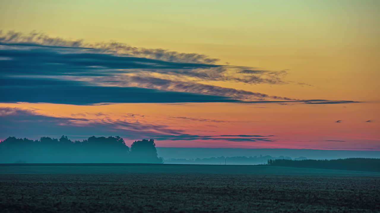 las nubes fluyen por el cielo del amanecer en una mañana fría causando una inversión sobre los campos de cultivo - lapso de tiempo