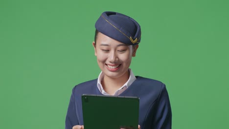 close up of asian woman air hostess using a tablet while standing in the green screen background studio