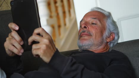 senior man using digital tablet on sofa 4k