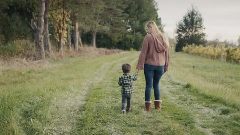 mother and son walk through the farm, the baby eats an apple