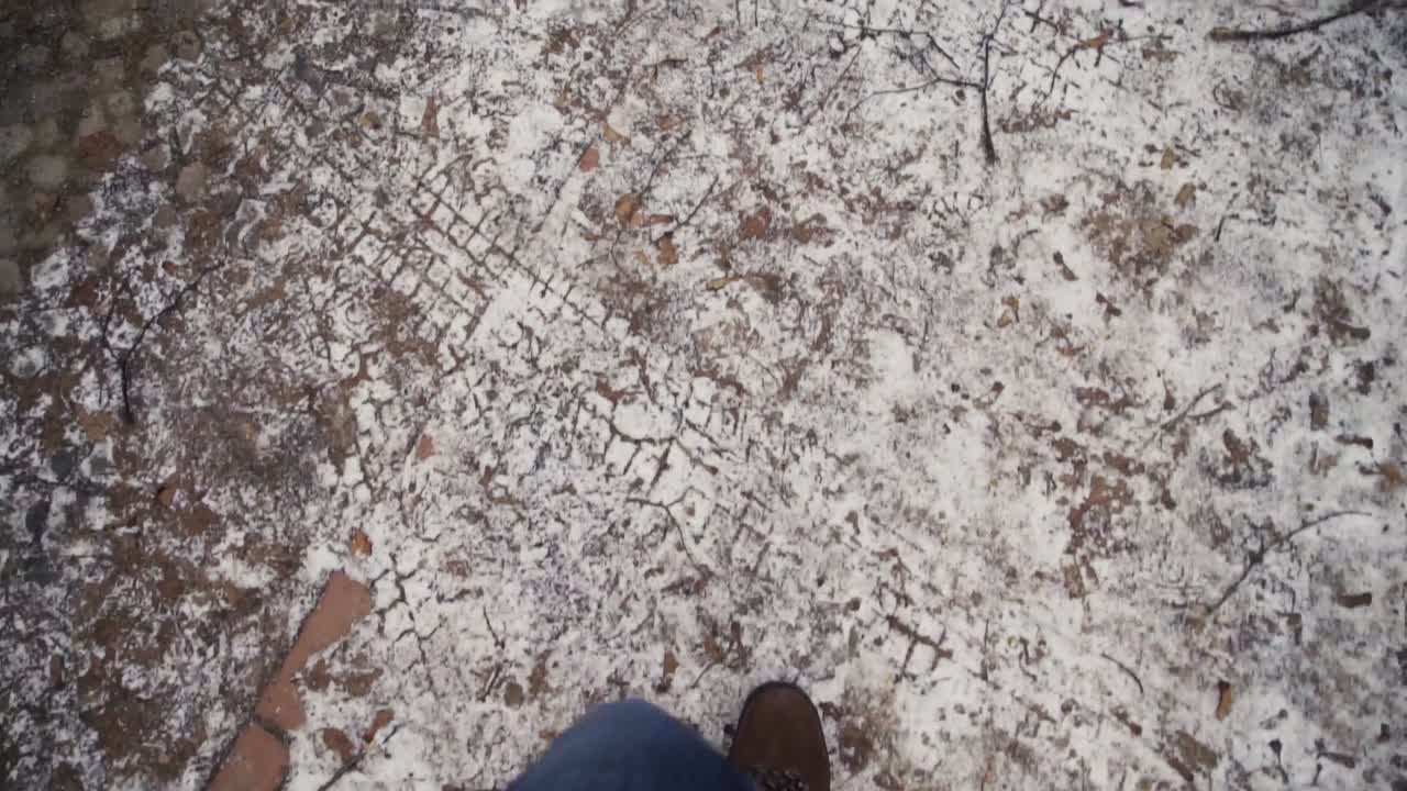 Male feet in jeans and winter shoes walking on frosted sidewalk, slow motion