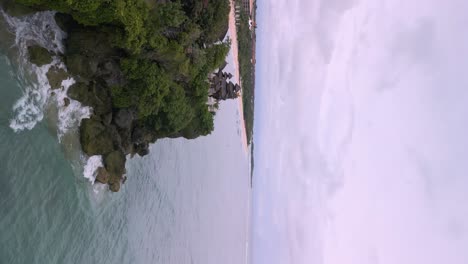 Vertical-video-of-a-hindu-tempel-on-a-ccliff-above-the-wild-blue-sea-in-Bali