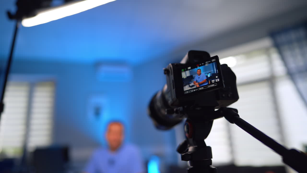 Camera on tripod taking video of a man shown on the display. Low angle view. Medic creates video for a blog. Selective focus