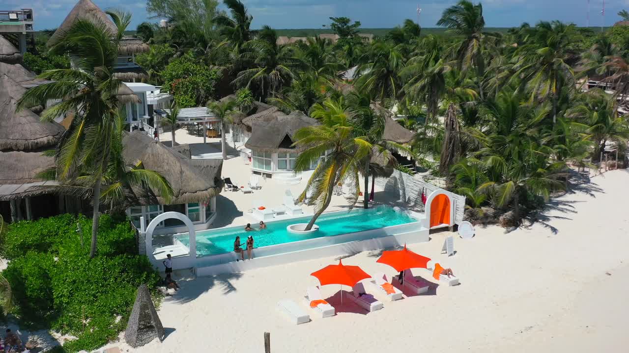 turistas relajándose en la piscina en el lujoso hotel bohemio en la playa tropical de arena blanca en tulum méxico, antena