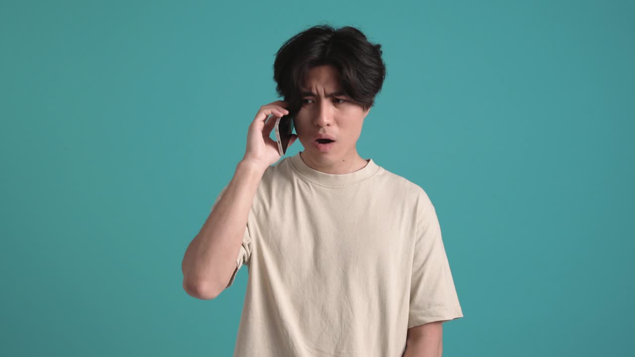 Displeased Asian man talking by phone