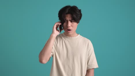 displeased asian man talking by phone
