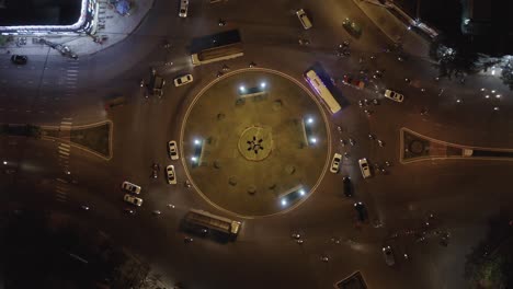 an aerial drone shot of rush hour traffic at roundabout intersection at night - ascending