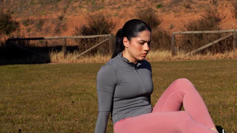 fit woman exercising legs and abs on grass in park. pan medium close-up, 4k