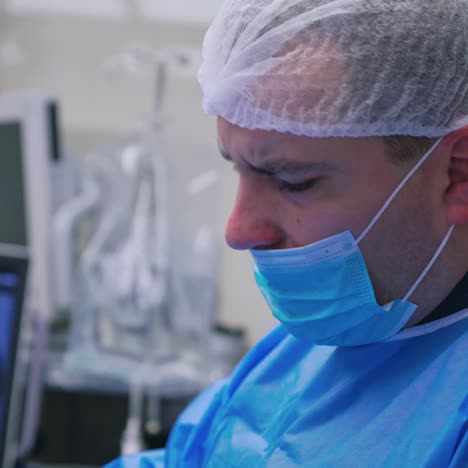 side view of a doctor's face in mask. male surgeon looking at monitor while performing an operation in a modern clinic.