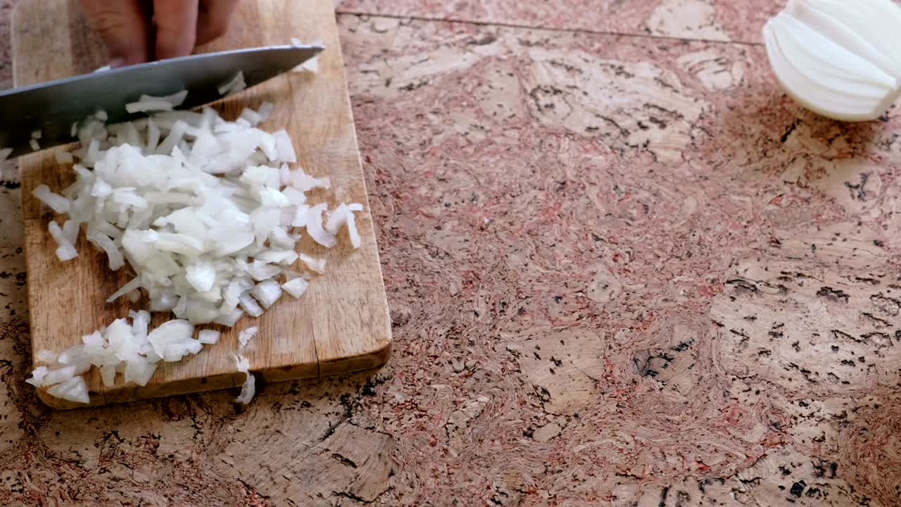 Man gently cuts the onion into small pieces. Man's hands close-up.