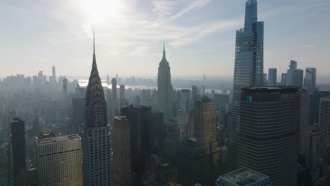 Vorwärts-Fliegen-über-Gebäude-Gegen-Sonne.-Dunstiger-Blick-Auf-Das-Historische-Chrysler-Und-Empire-State-Building-Und-Das-Moderne-Vanderbilt.-Manhattan,-New-York-City,-Vereinigte-Staaten