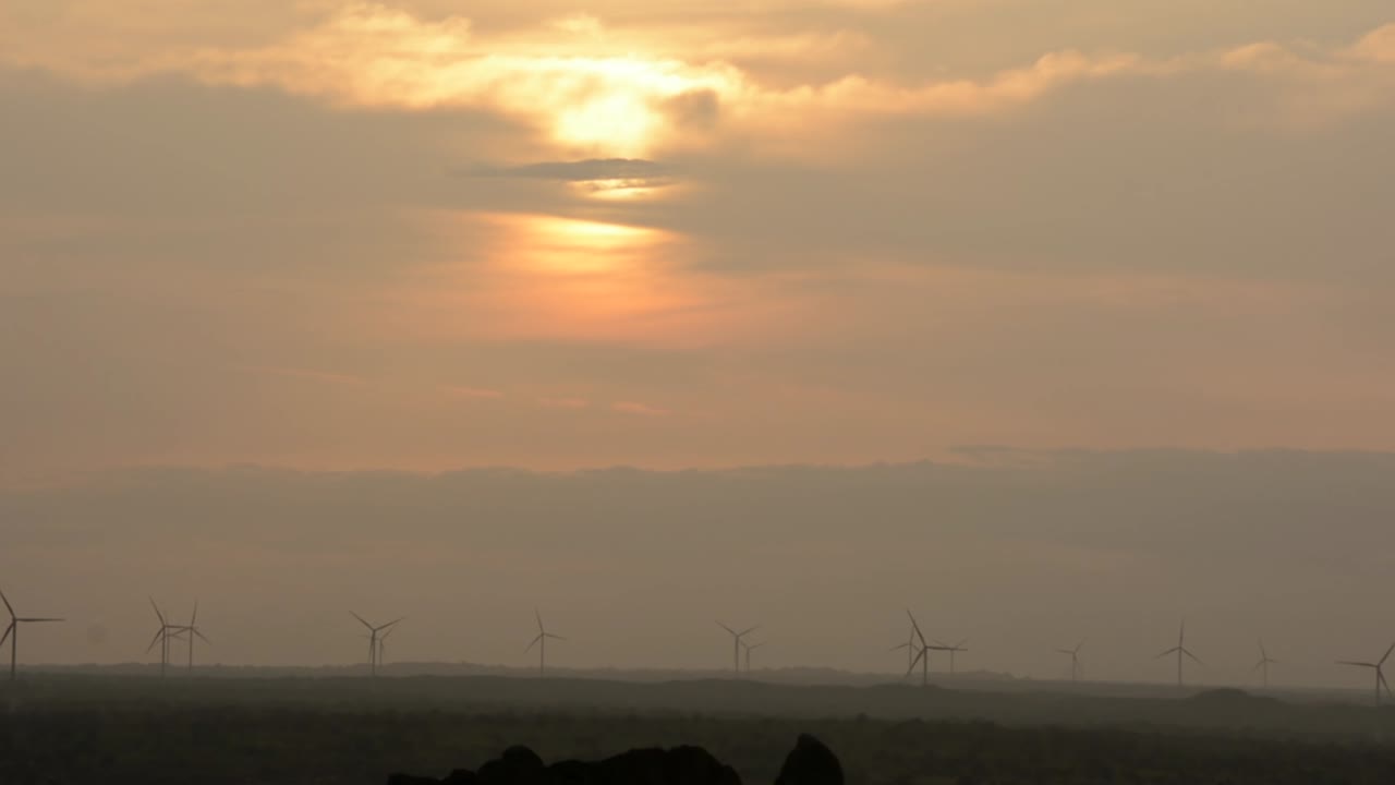 spinning wind turbines for electrical power generation at a beautiful sunset with the colorful cloudy sky in Raichur, India. Modern technology of environment friendly energy production
