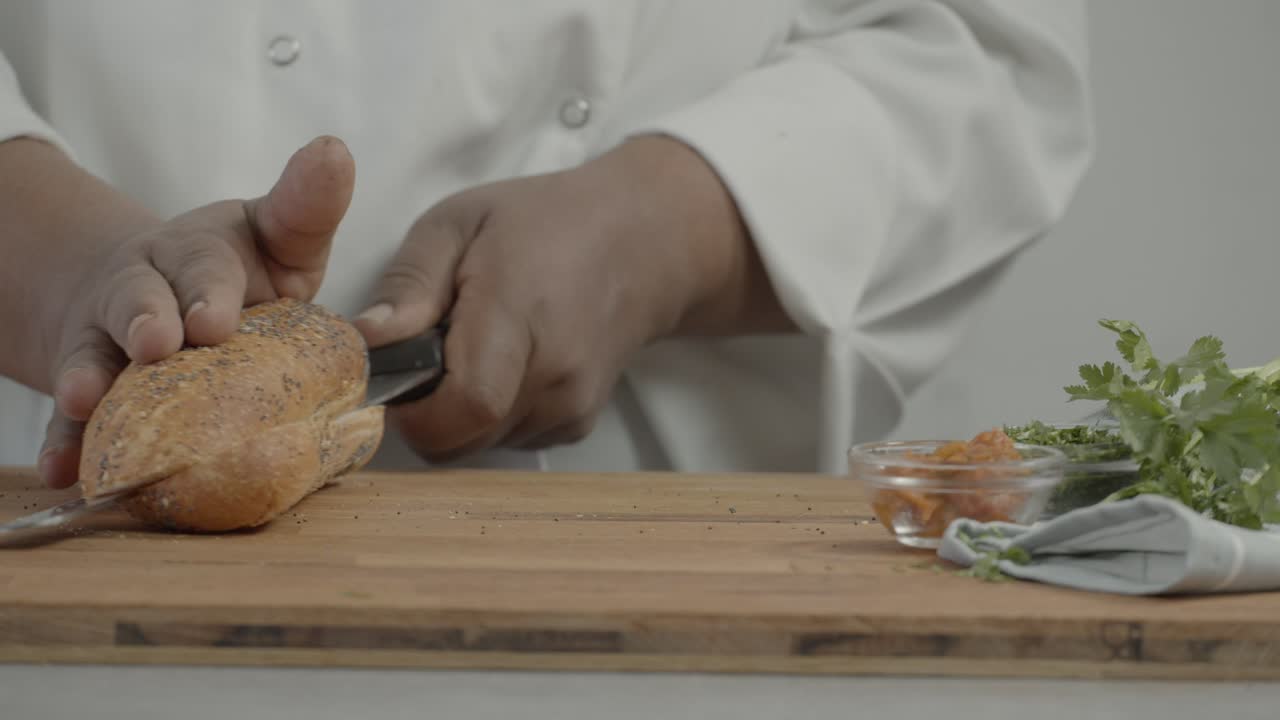 close up of chef's hand cutting bread. man cuts fresh bread with a knife on a wooden cutting board. Breakfast or lunch concept