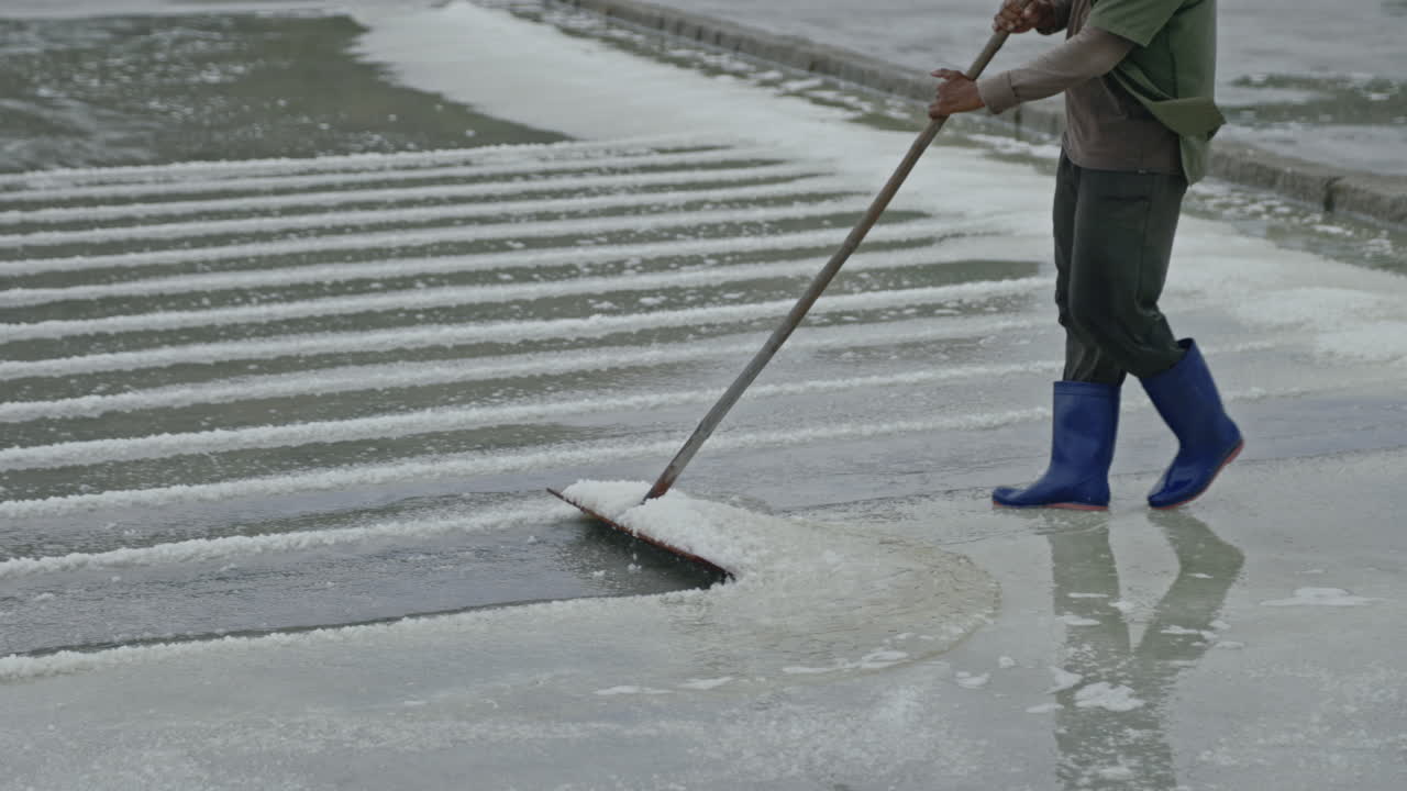 A person harvesting salt in a salt pan
