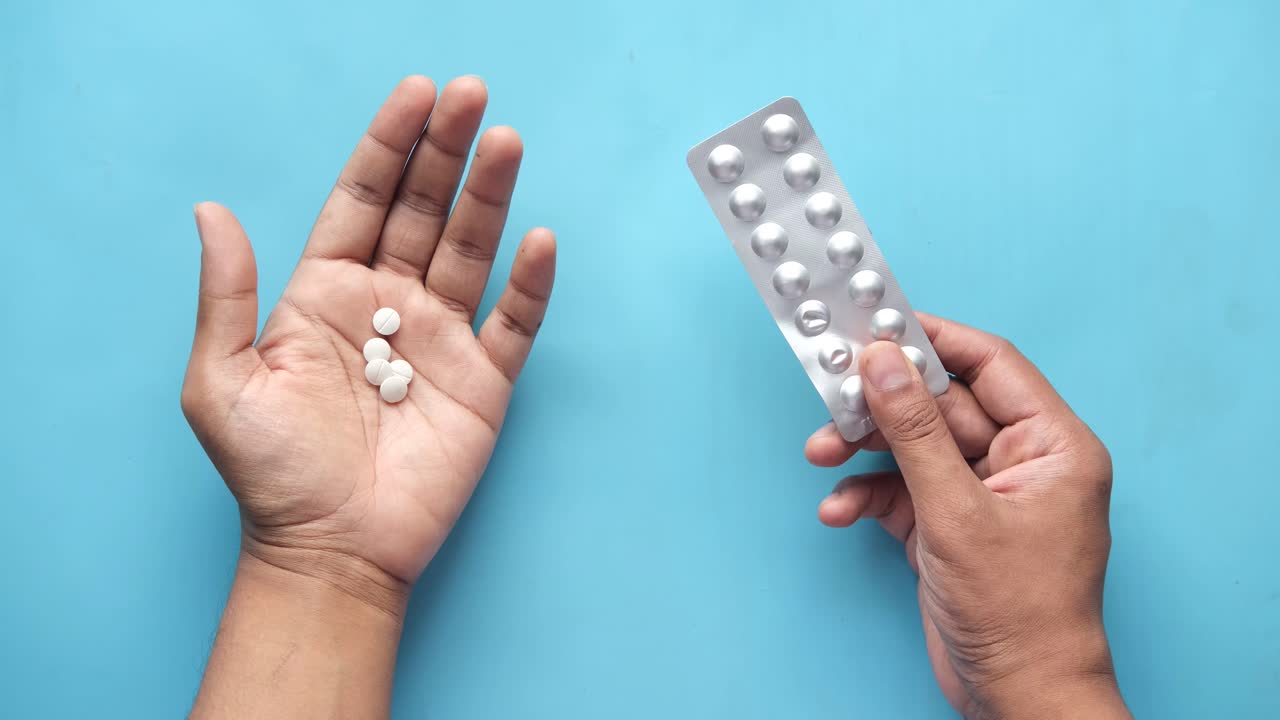 con pastillas en la mano y un paquete de medicamentos en blister