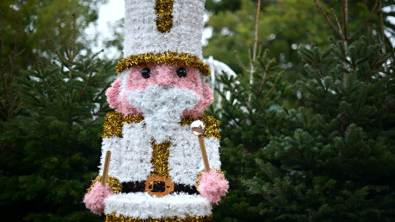 Decorative Christmas nutcracker soldier figure displayed outdoors with trees in the background