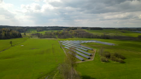 aerial trucking shot of renewable solar panel farm in green countryside during sunny day in poland