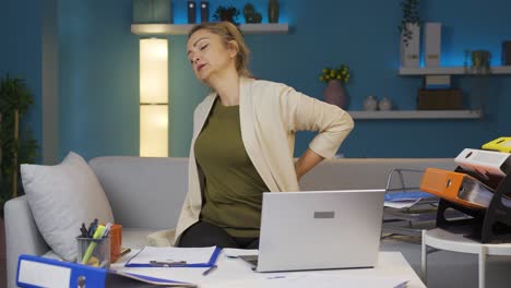 una mujer que trabaja en la oficina tiene dolor de espalda.