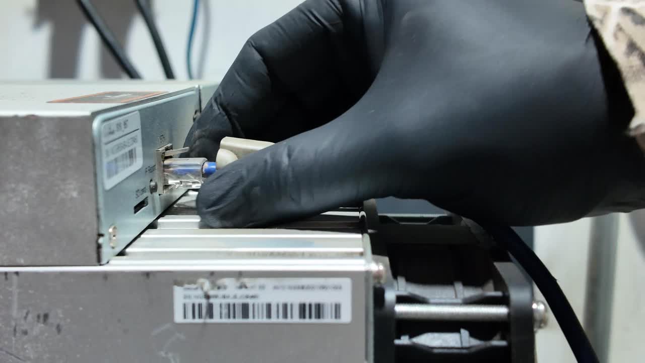 Close-up view of gloved hand disconnecting blue Ethernet cable to an industrial electronic device. Networking hardware, maintenance and connectivity,