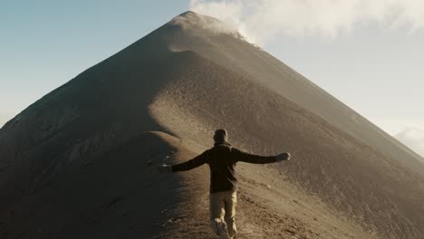 excursionista corriendo por la cresta del volcán fuego hacia un cráter activo en guatemala