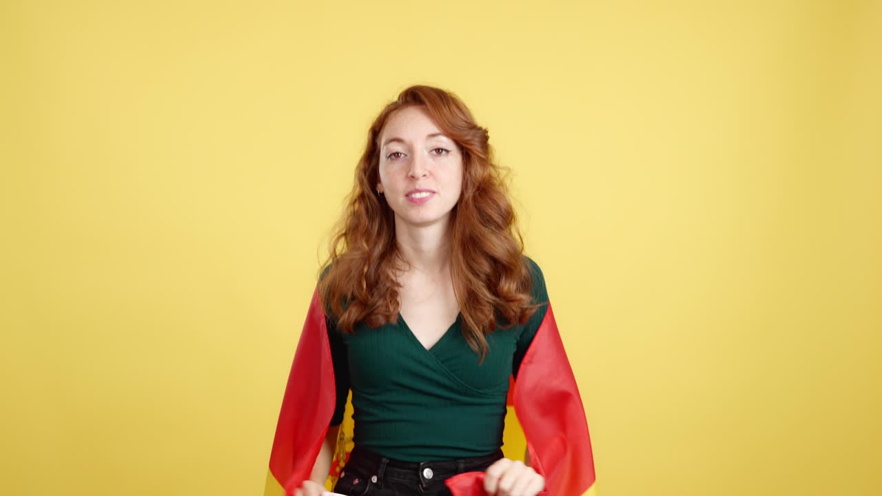 Happy Redhead Woman Waving Spanish Flag on Yellow Background
