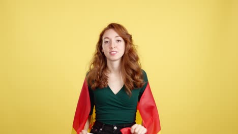 happy redhead woman waving spanish flag on yellow background
