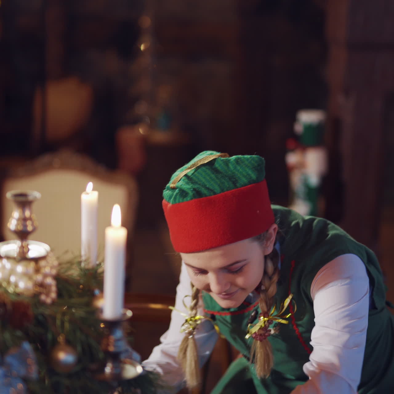 Curious elf looking at envelopes in the decorated room. Candles glowing on the table and a tricky elf holding letters and talking to someone. Christmas time.