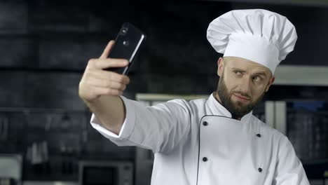 el chef tomando una foto en la cocina. el retrato del chef tomando una selfie en el teléfono móvil.