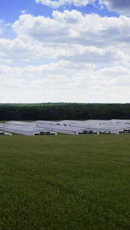 modern farm among agricultural fields. white farm buildings on beautiful nature background. agricultural complex on rural landscape. motion camera to the left. vertical video