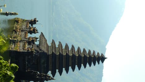 vertical slow motion panning shot of pura segara ulun danu batur a historical temple at volcanic lake batur on a sunny day during the beautiful summer trip through bali indonesia