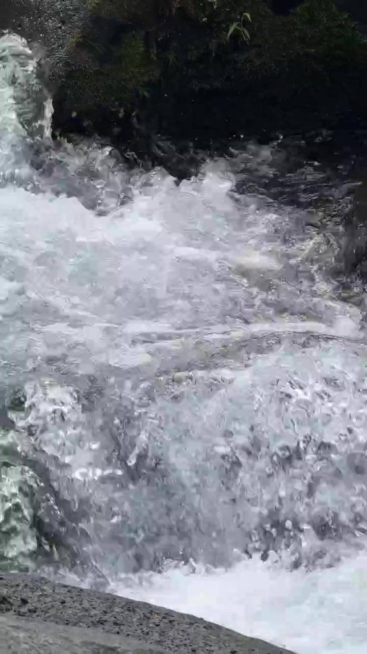 Primo piano di acqua impetuosa che scorre su rocce in un ruscello