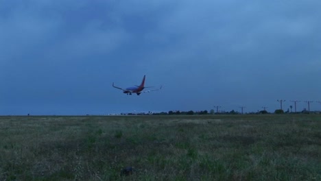 a jet airplane lands on an airport runway against darkened skies