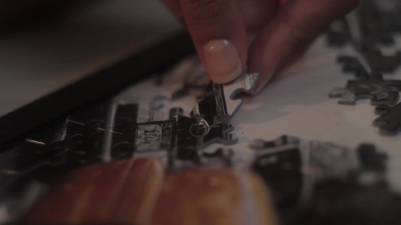Some footage showing a hand adding a piece to an uncomplete puzzle.