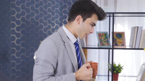 young businessman working hard in the office and drinking his coffee.