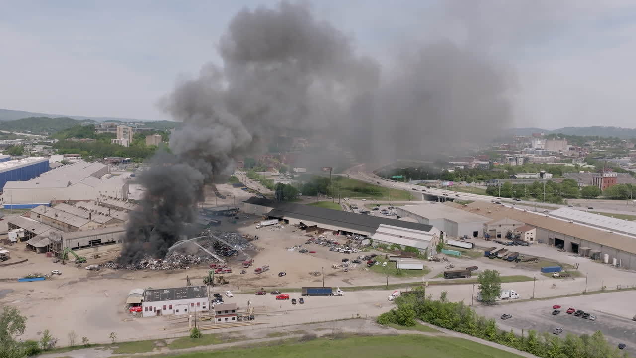 amplias imágenes estáticas aéreas de un gran incendio industrial con bomberos luchando contra él con una autopista en el fondo en chattanooga, tn