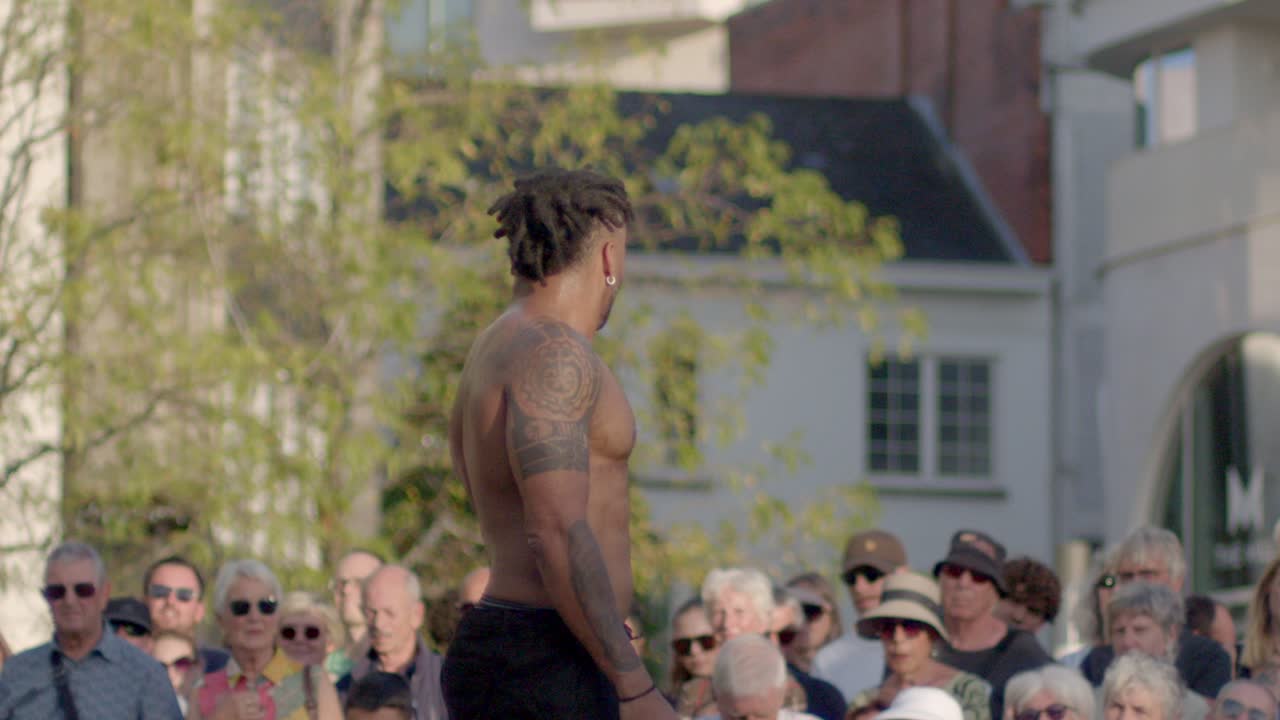 Side profile of a muscular shirtless black man during street dance performance, Handheld shot
