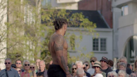 side profile of a muscular shirtless black man during street dance performance, handheld shot