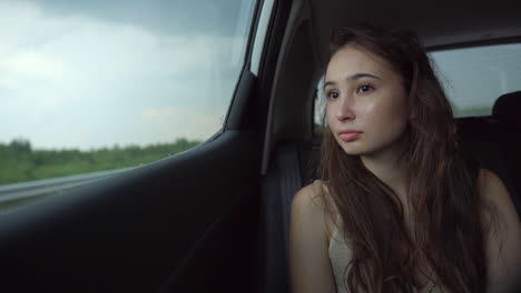 young woman looking out car window on rainy day