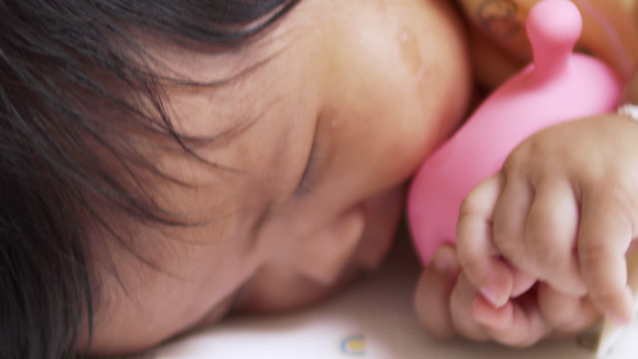 Features an Asian infant interacting with a rubber mushroom, emphasizing the role of toys in fostering developmental skills during infancy