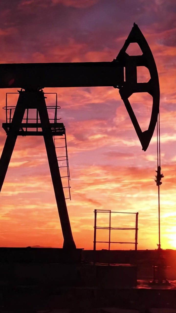 Silhouetted Oil Pumping Unit Against a Colorful Sunset Sky Reflecting Vibrant Hues of Orange, Purple, and Pink, Marking the End of Another Productive Day in Energy Production