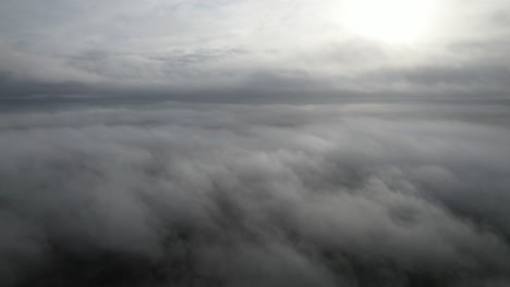 aerial pan view above fog low level cloud sun bursting through